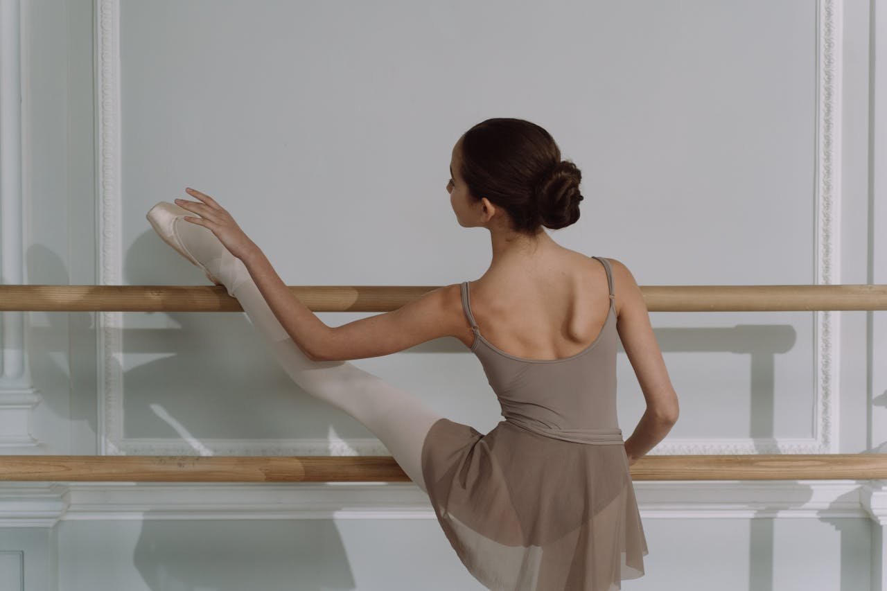 Elegant young ballet dancer stretching on a barre, showcasing grace and poise.
